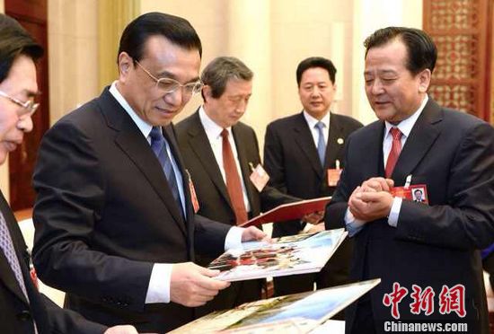 代表拿照片介紹棚戶區新貌替棚戶居民謝總理（圖）