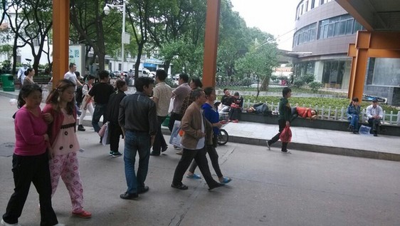 醫(yī)院院內(nèi)“人滿為患”，石凳石桌上坐滿了疲憊的患者和家屬