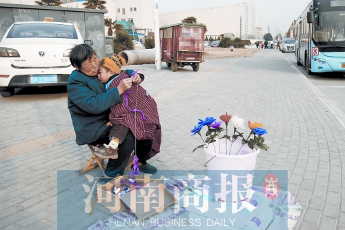 在鄭州市國基路邊，何志蘭一邊照顧4歲的孫子，一邊忙里偷閑編花