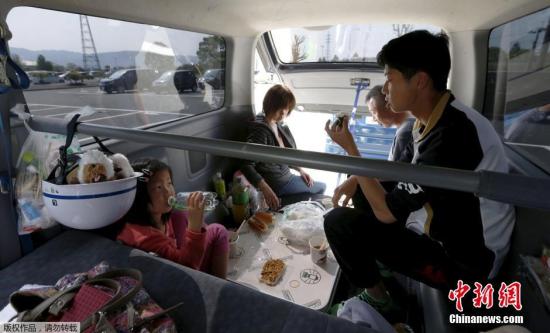 當?shù)貢r間4月19日，日本熊本縣益城町匯集眾多地震避難者的停車場內(nèi)，一家人在汽車內(nèi)吃飯。
