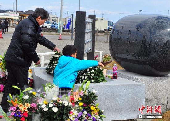 資料圖：當年人員損失最為慘重的宮城縣內各地，民眾在當地建起的慰靈碑前獻花祭悼。王健 攝